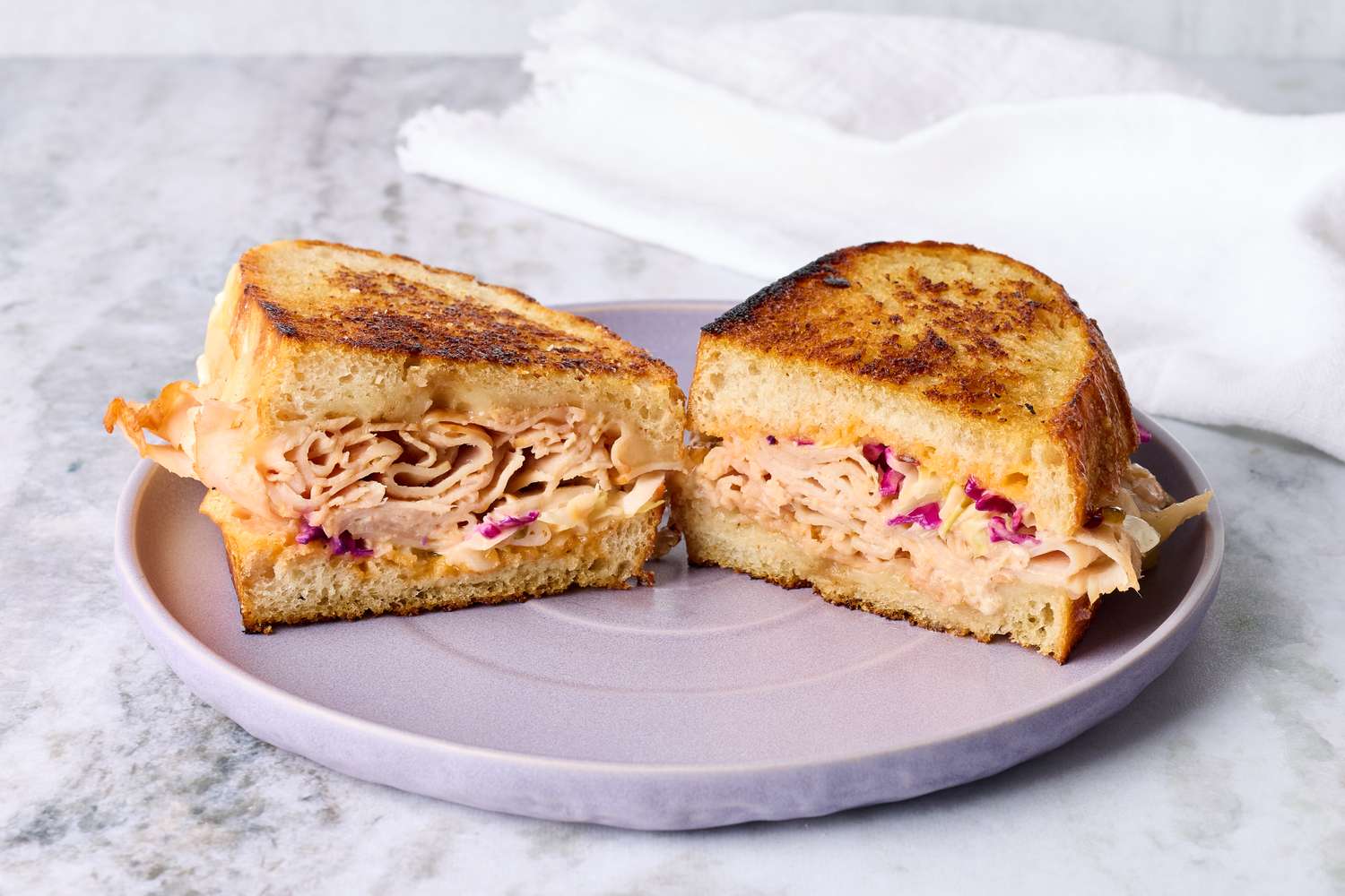 A sandwich with meat and slaw on toasted bread halves on a plate