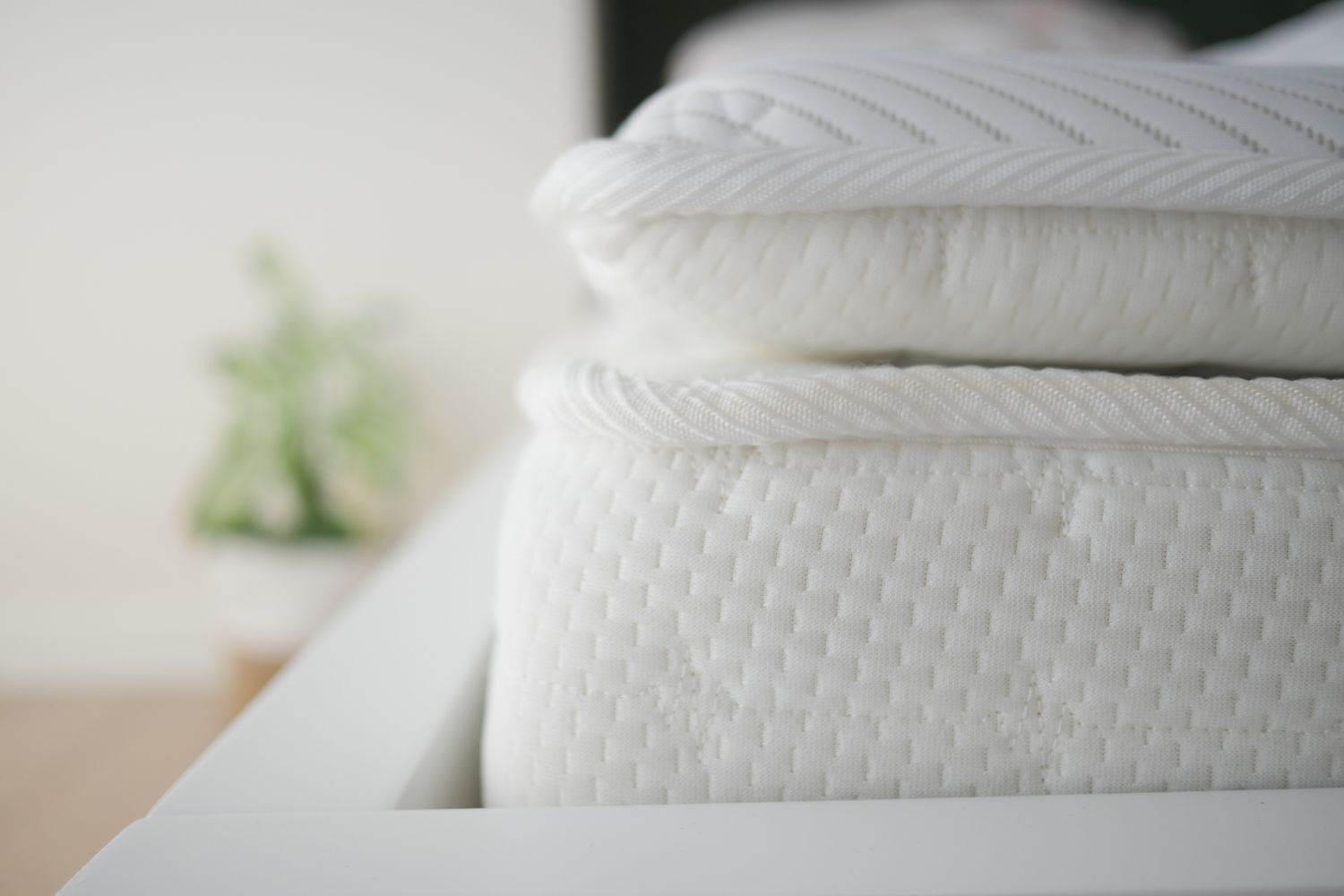 A closeup view of a stacked mattress and pillow on a bed frame