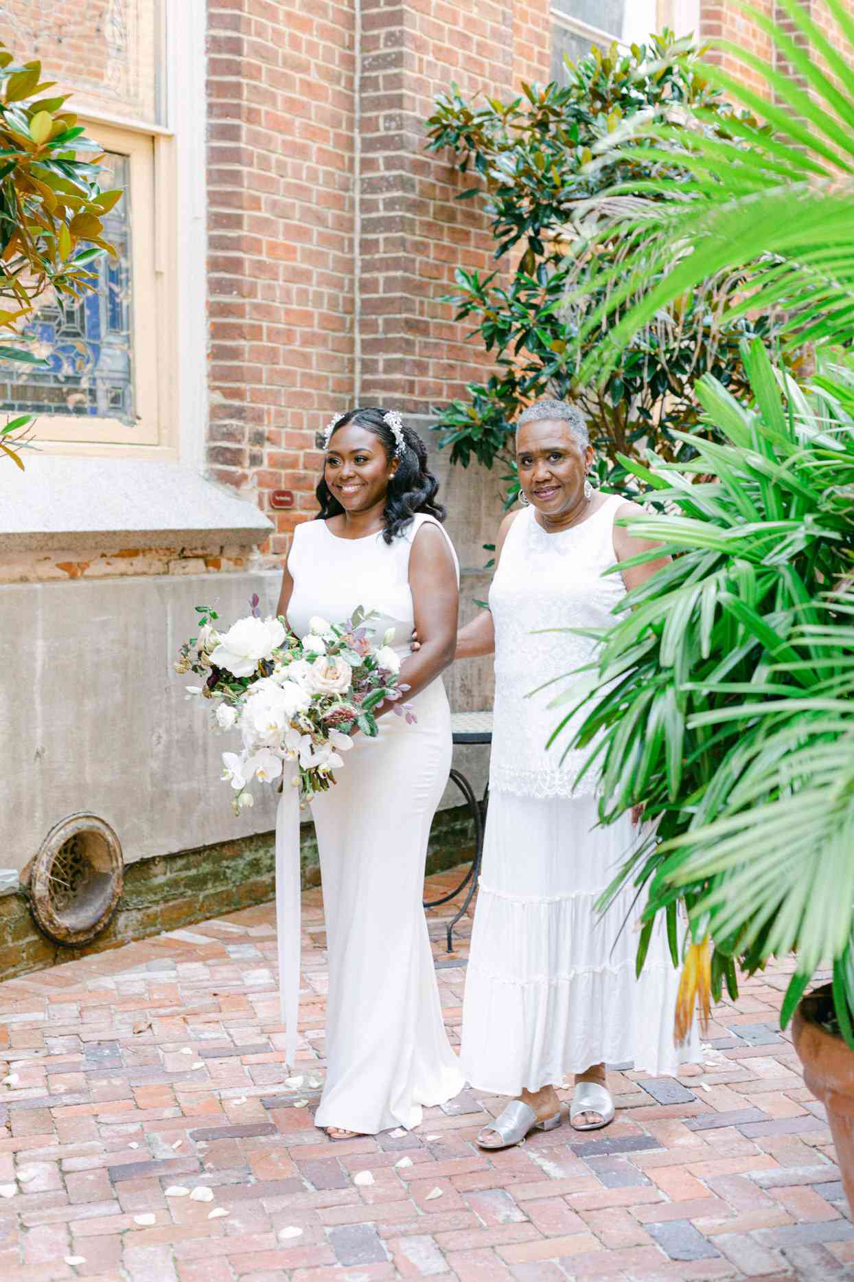 bride and mother processing for wedding in brick courtyard