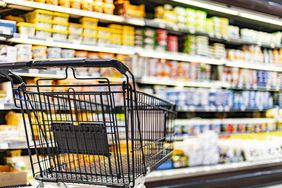 A shopping cart by a store shelf in a supermarket. 