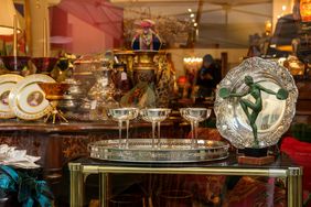 A store display featuring decorative vintage items including plates goblets and an artdecostyle sculpture