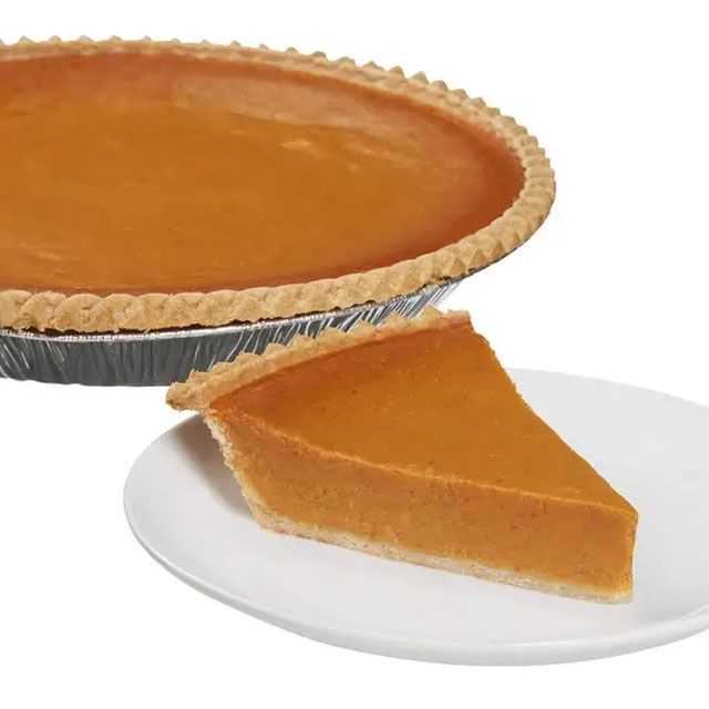 Whole pumpkin pie with a slice served on a plate