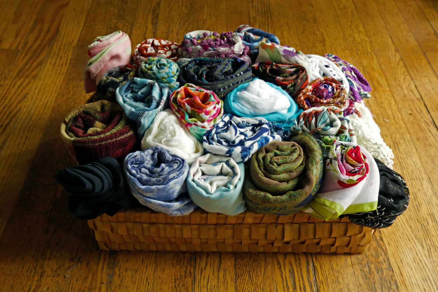 A basket of rolled-up scarves in clashing patterns.