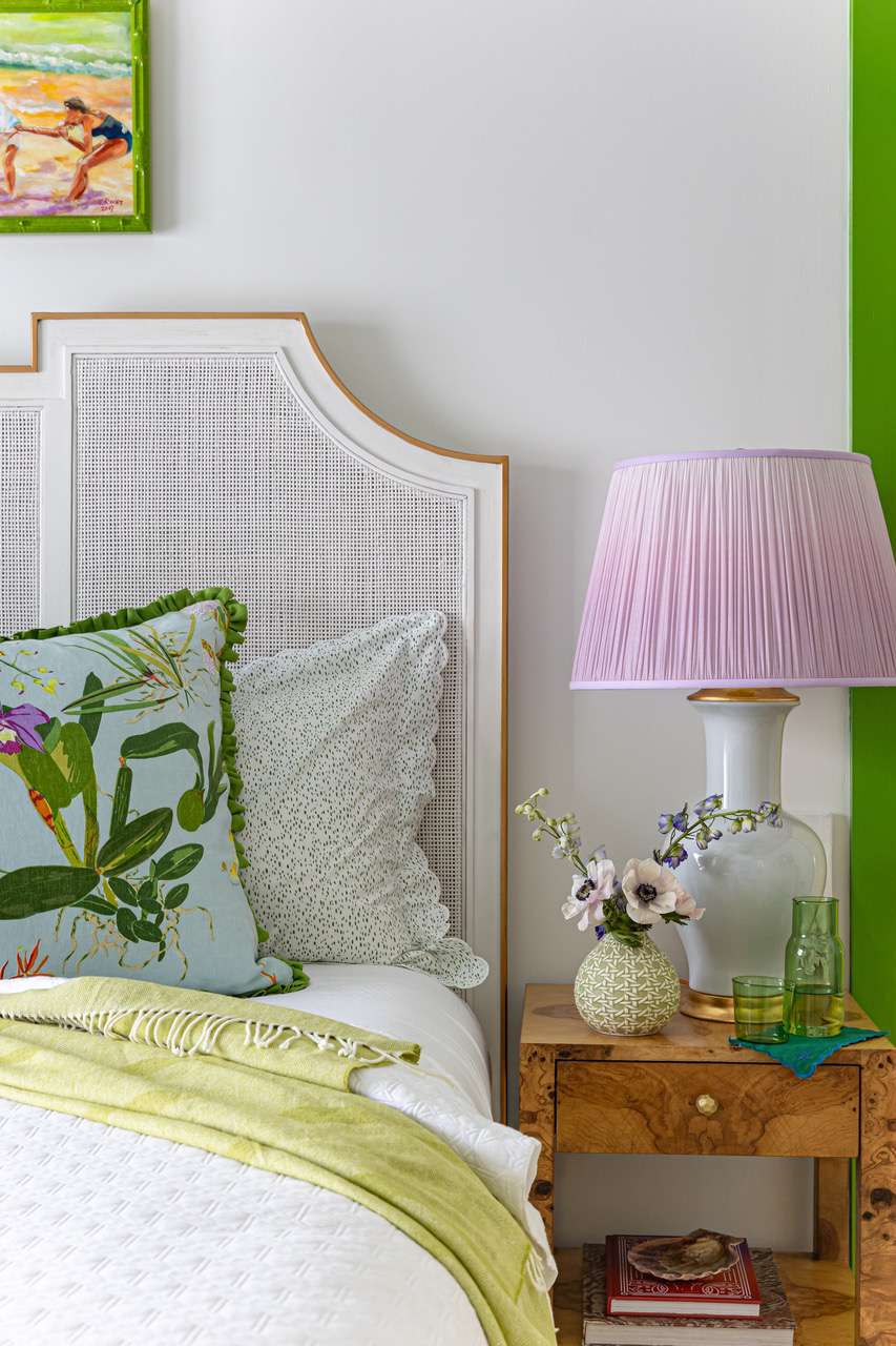 a white bedroom with a bedside lamp that has a pink shade 