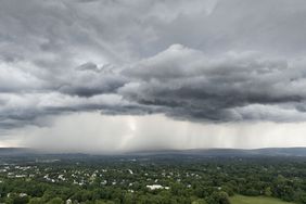 Cloudy sky with rain over a green landscape