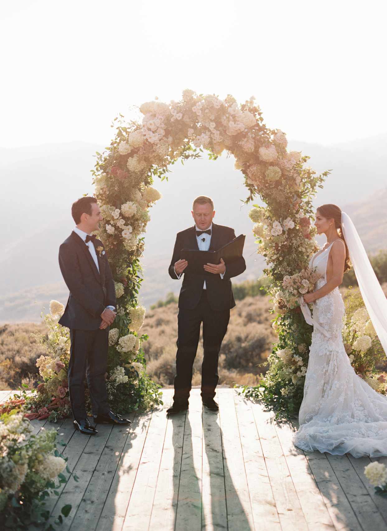 bride and groom during wedding ceremony outside under floral arch