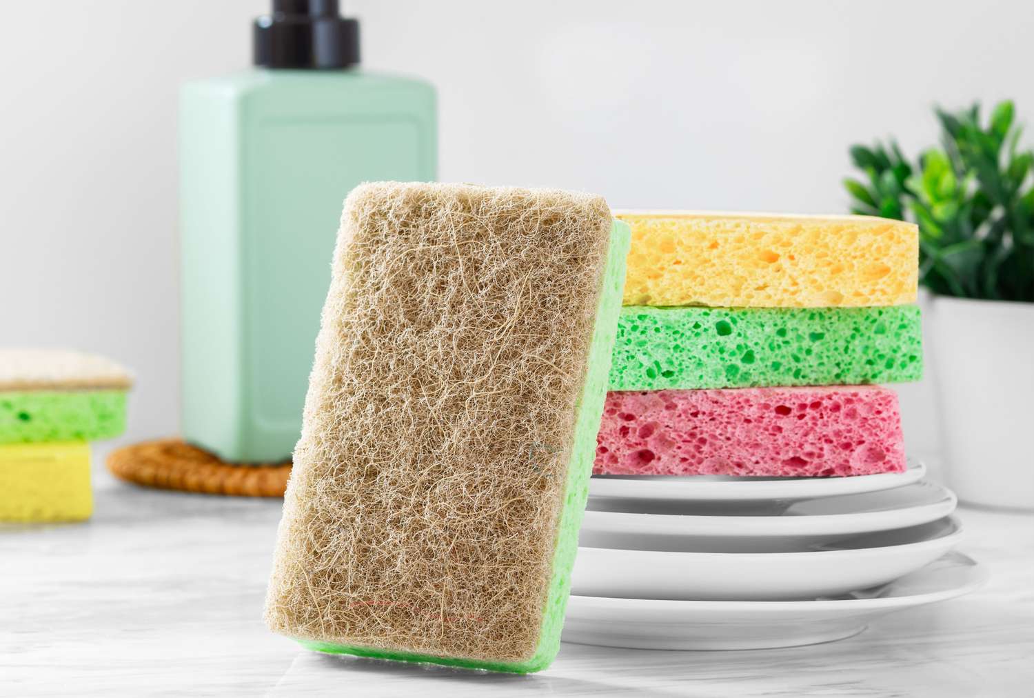 Cleaning sponges stacked on plates with a dispenser in the background