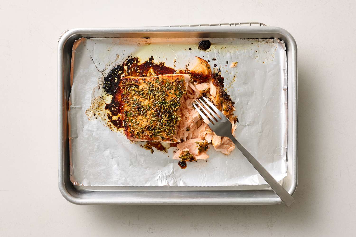 Salmon fillet cooked on a baking sheet with a fork placed nearby