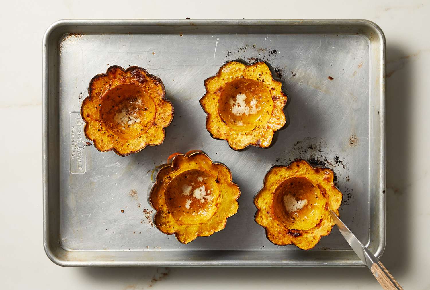 overhead view of cooked acorn squash on pan with knife