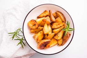 Bowl of roasted potato wedges garnished with rosemary