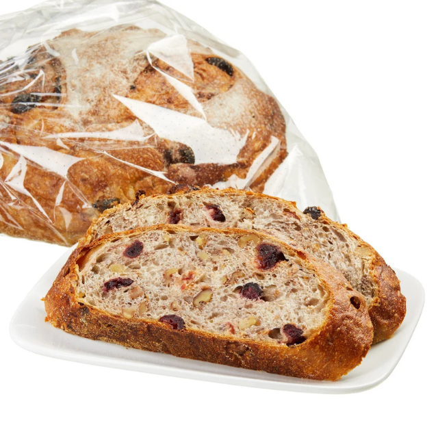 Sliced loaf of bread with raisins and nuts on a white plate