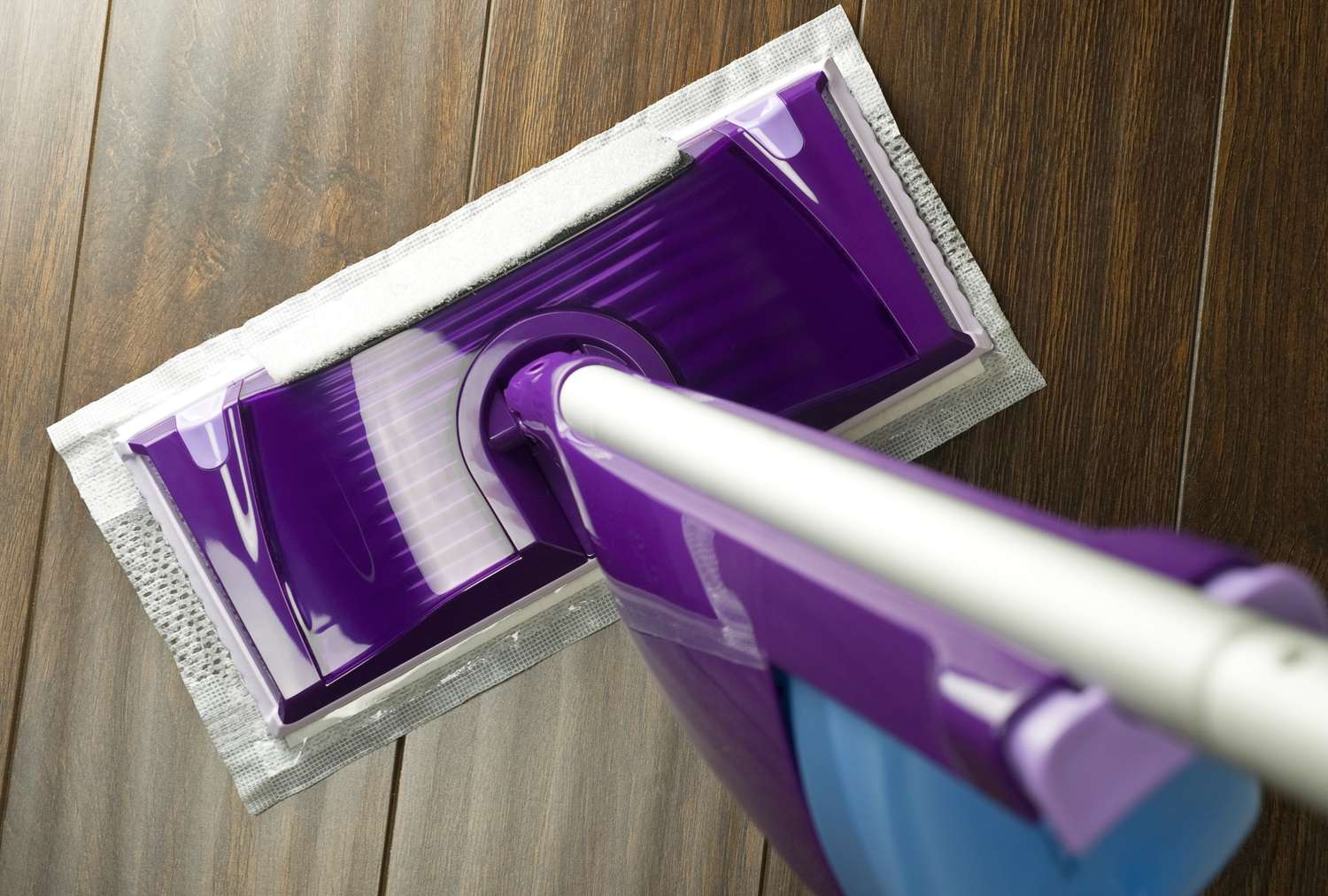 A cleaning mop with a disposable pad on a hardwood floor