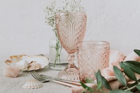 A set of ornate glasses and cutlery arranged with decorative items and greenery on a table