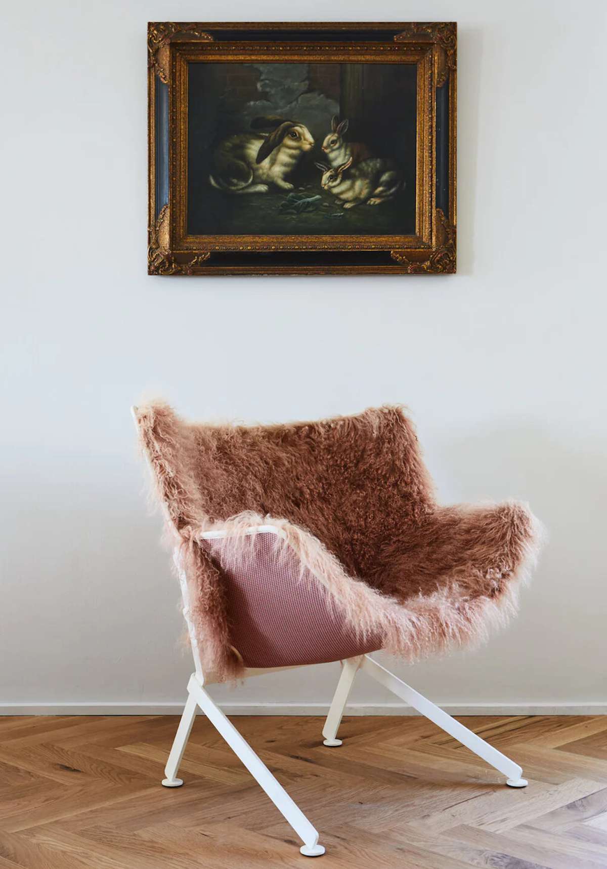 A pink chair in front of a white wall