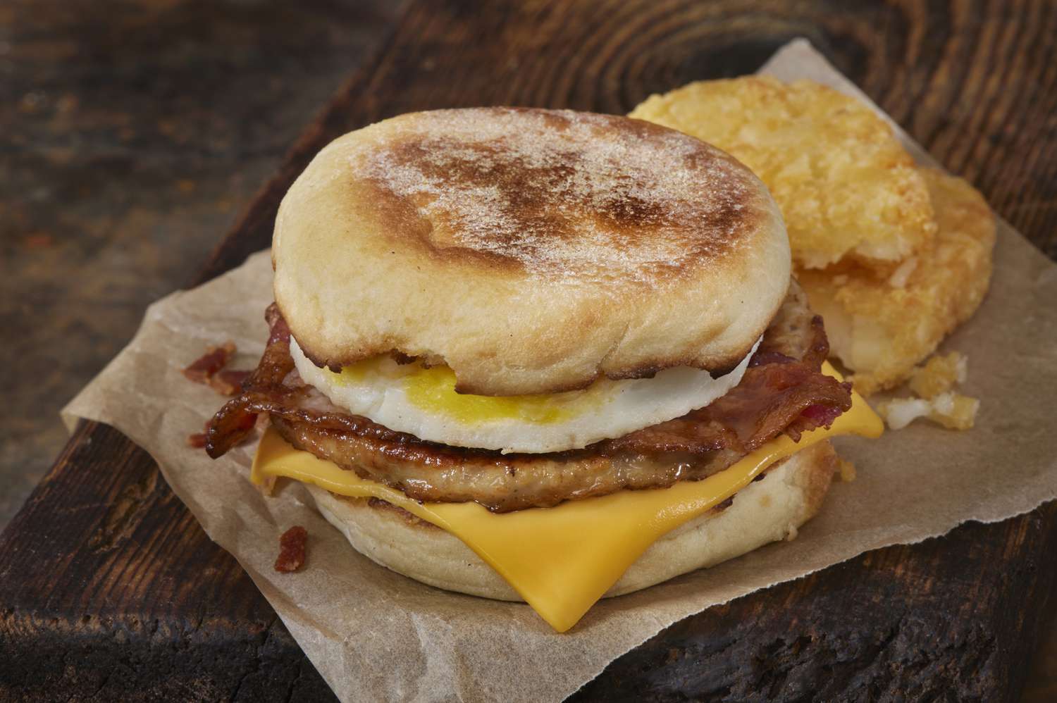 english muffin breakfast sandwich with egg, bacon, sausage, and cheese
