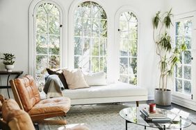 A welldecorated living room with arched windows a chaise lounge and plants