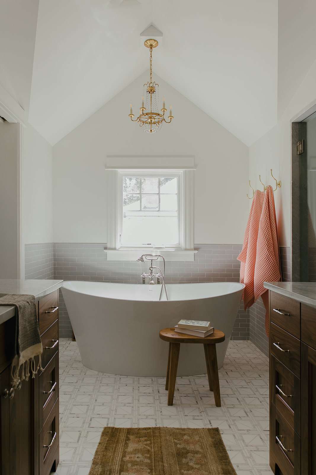 A bathroom with a freestanding bathtub positioned in front of a window, flanked by brown cabinets