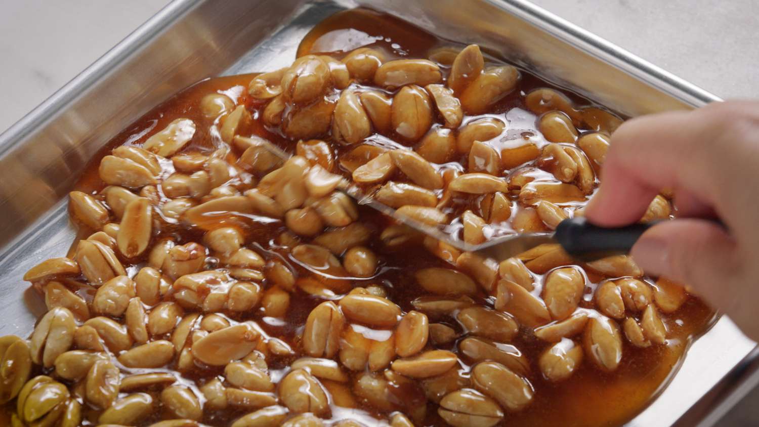 spreading peanut brittle in tray