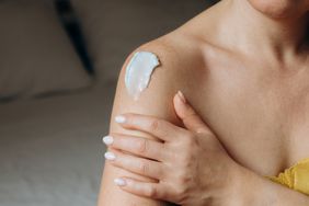 A person applying cream to their shoulder
