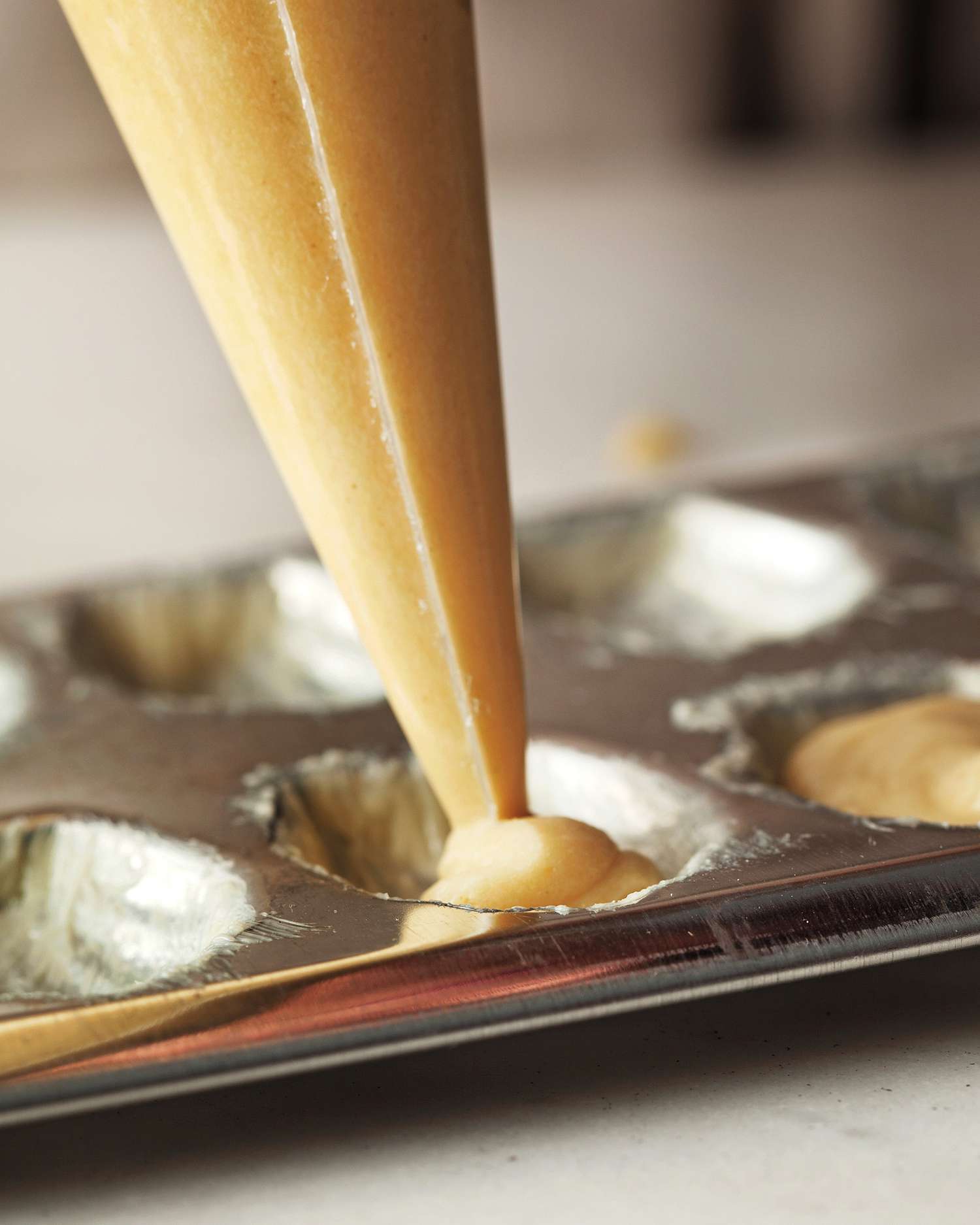 Piping batter into madeleine pan