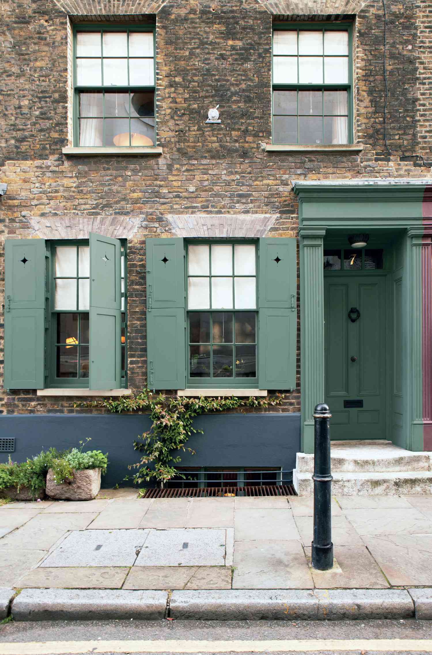 Green front door and shutters against brick home