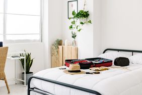 A guest room with a suitcase and travel items placed on a bed