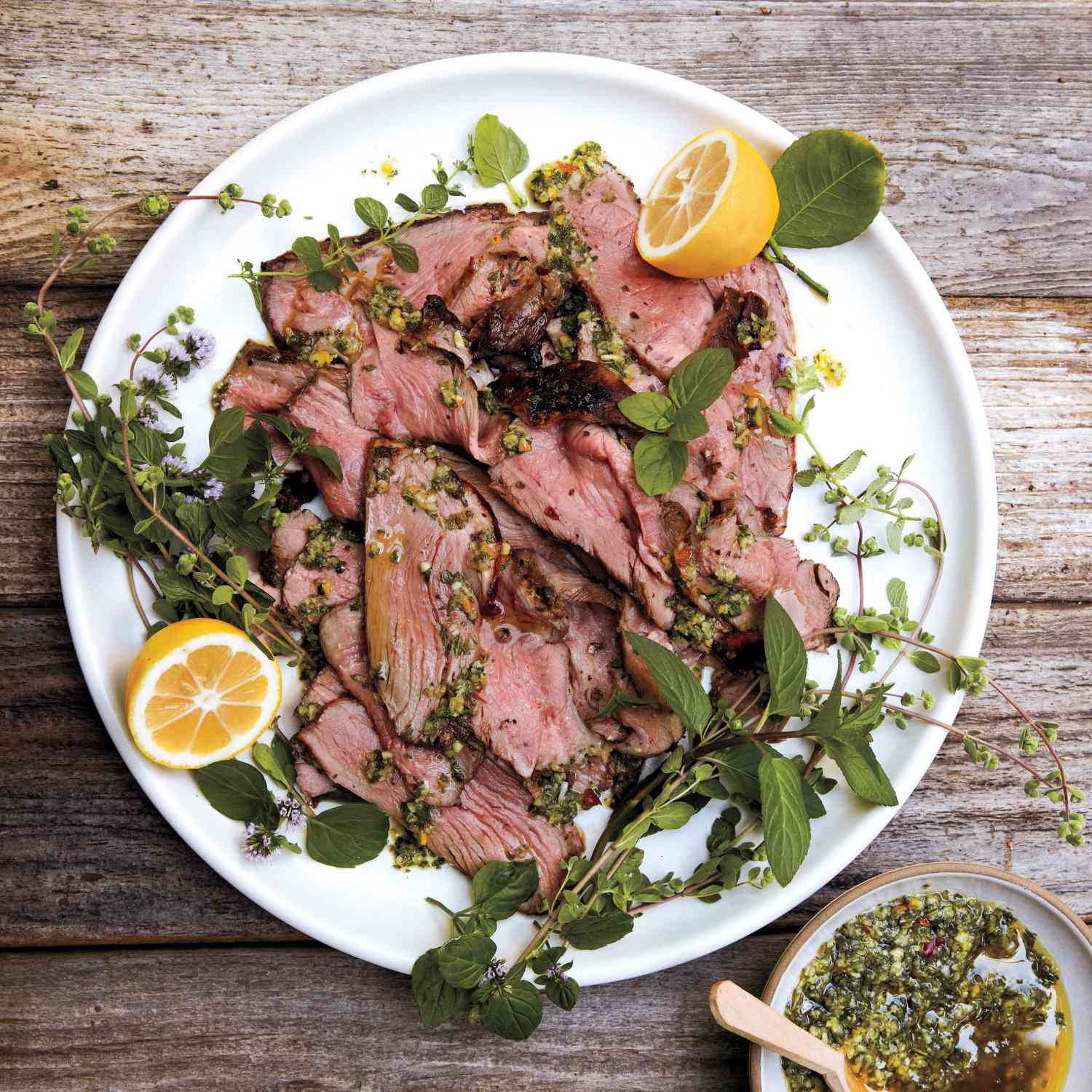 sliced lamb on a plate with herbs and lemon