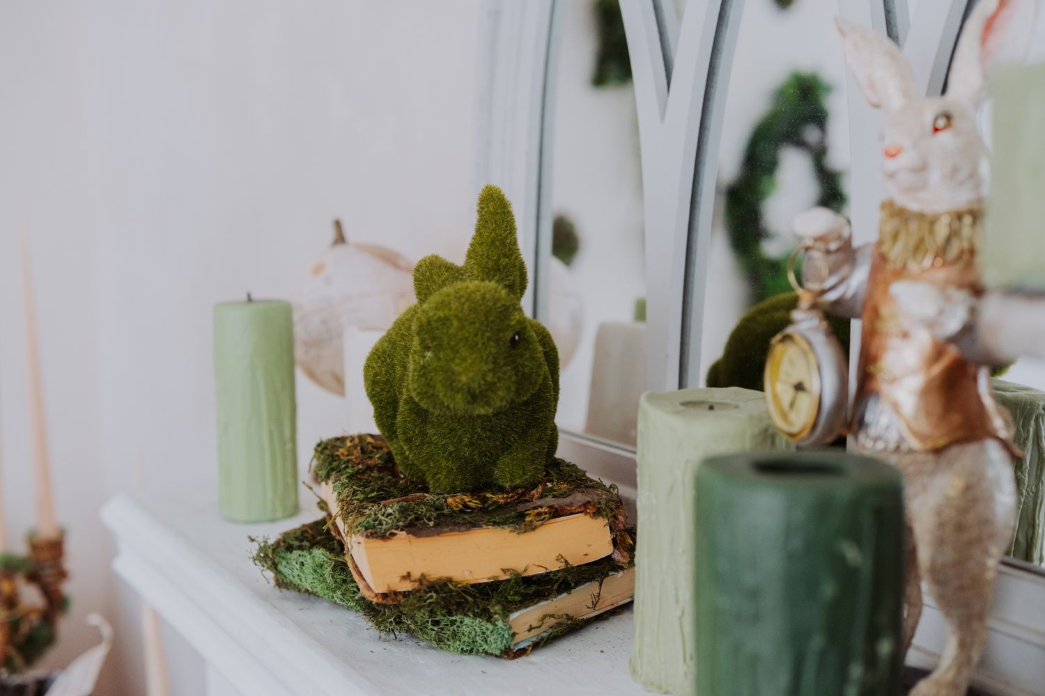 Decorative items including a moss rabbit figurine candles and a rabbit with a pocket watch