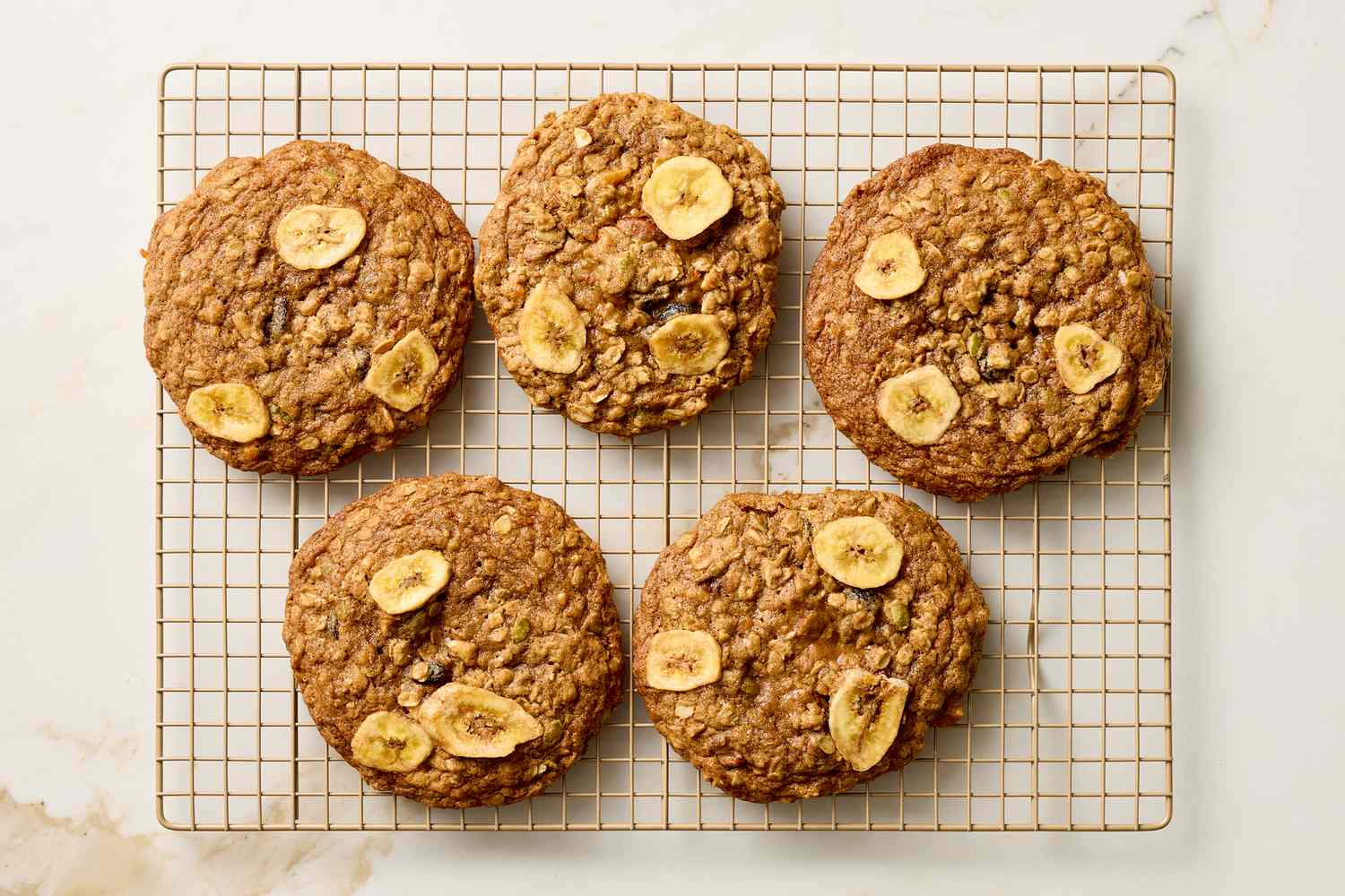 Five large cookies with banana slices on a cooling rack