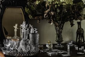 An arrangement of glassware, a mirror, and a bouquet of flowers on a table
