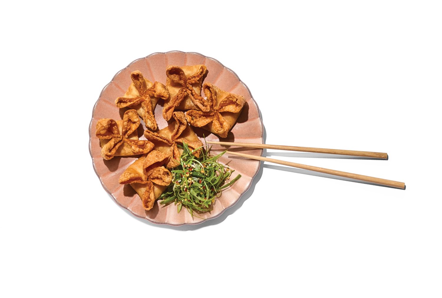 Plate with crispy wontons chopsticks and greens garnish