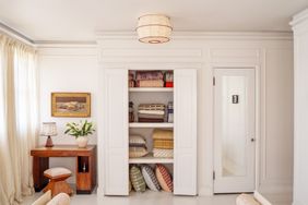 Interior with a builtin shelf containing folded linen a small desk setup and a door to the right