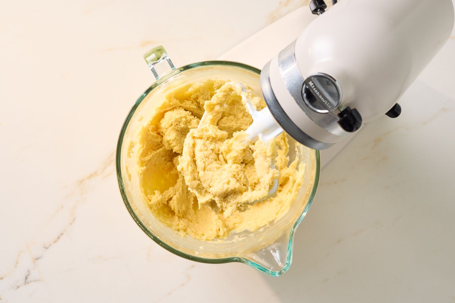 Dough mixture in a glass bowl attached to a stand mixer