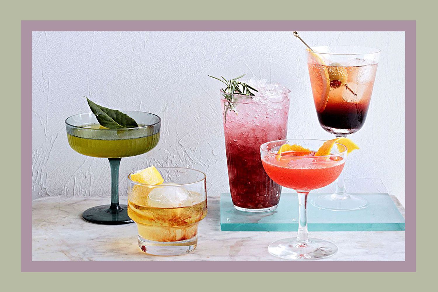 A variety of summer cocktails presented on a table, featuring garnishes and elegant glassware