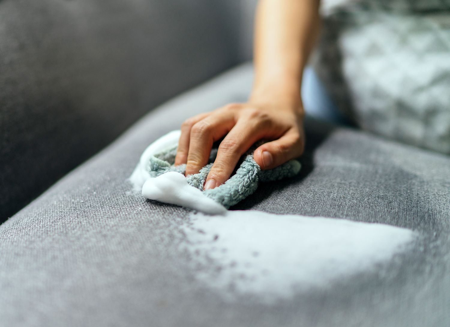 woman cleaning a sofa cushion with a rag