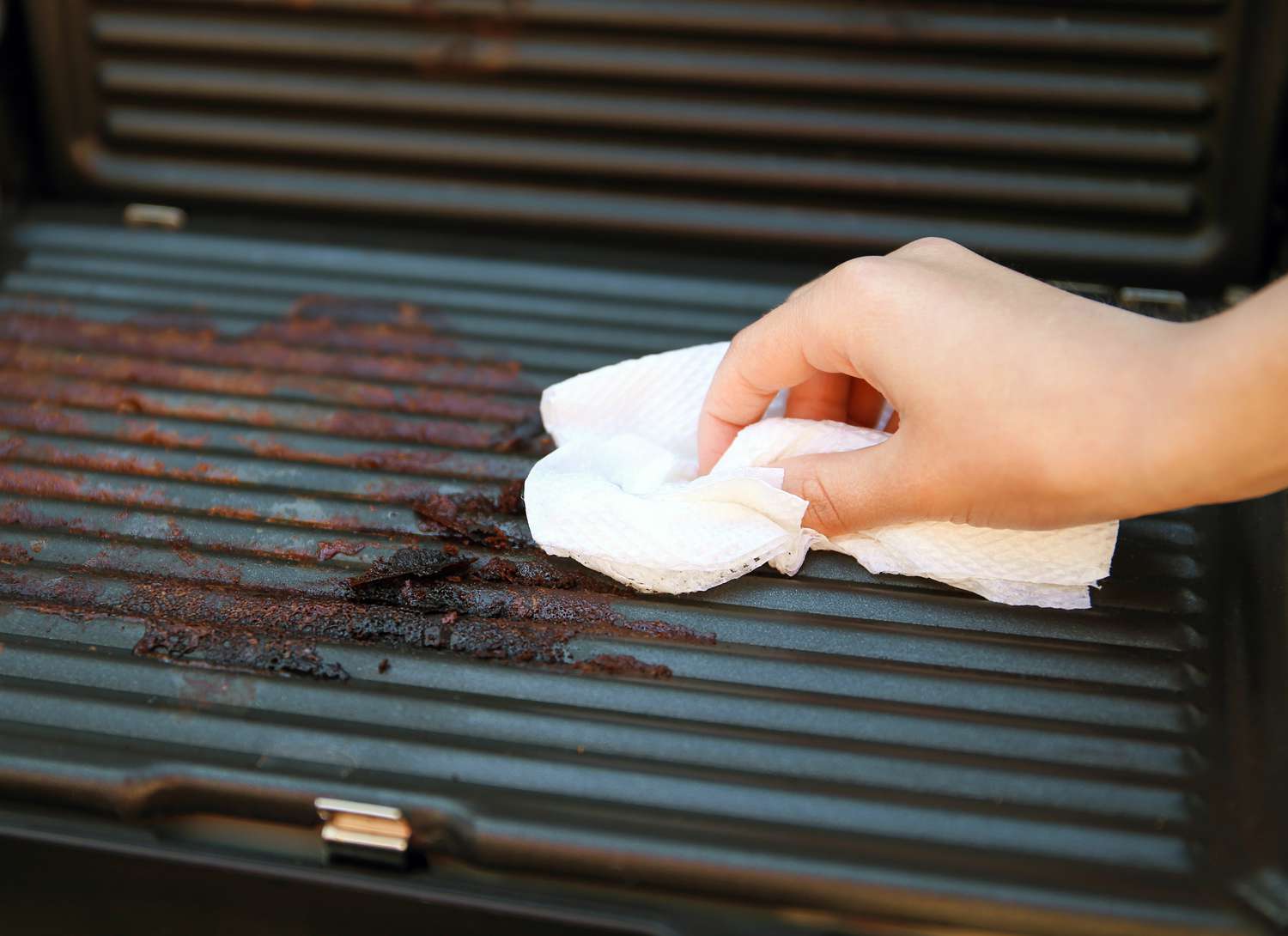 woman cleaning a grill with a cloth