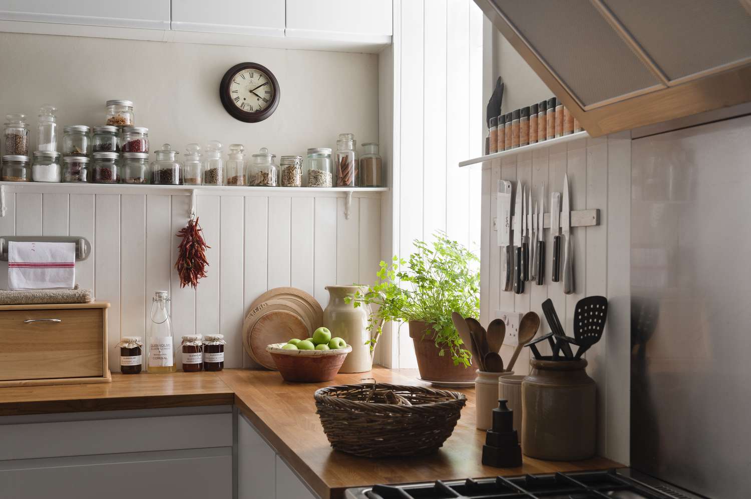 Open shelving and solid oak work surfaces in kitchen with white wooden wall panels