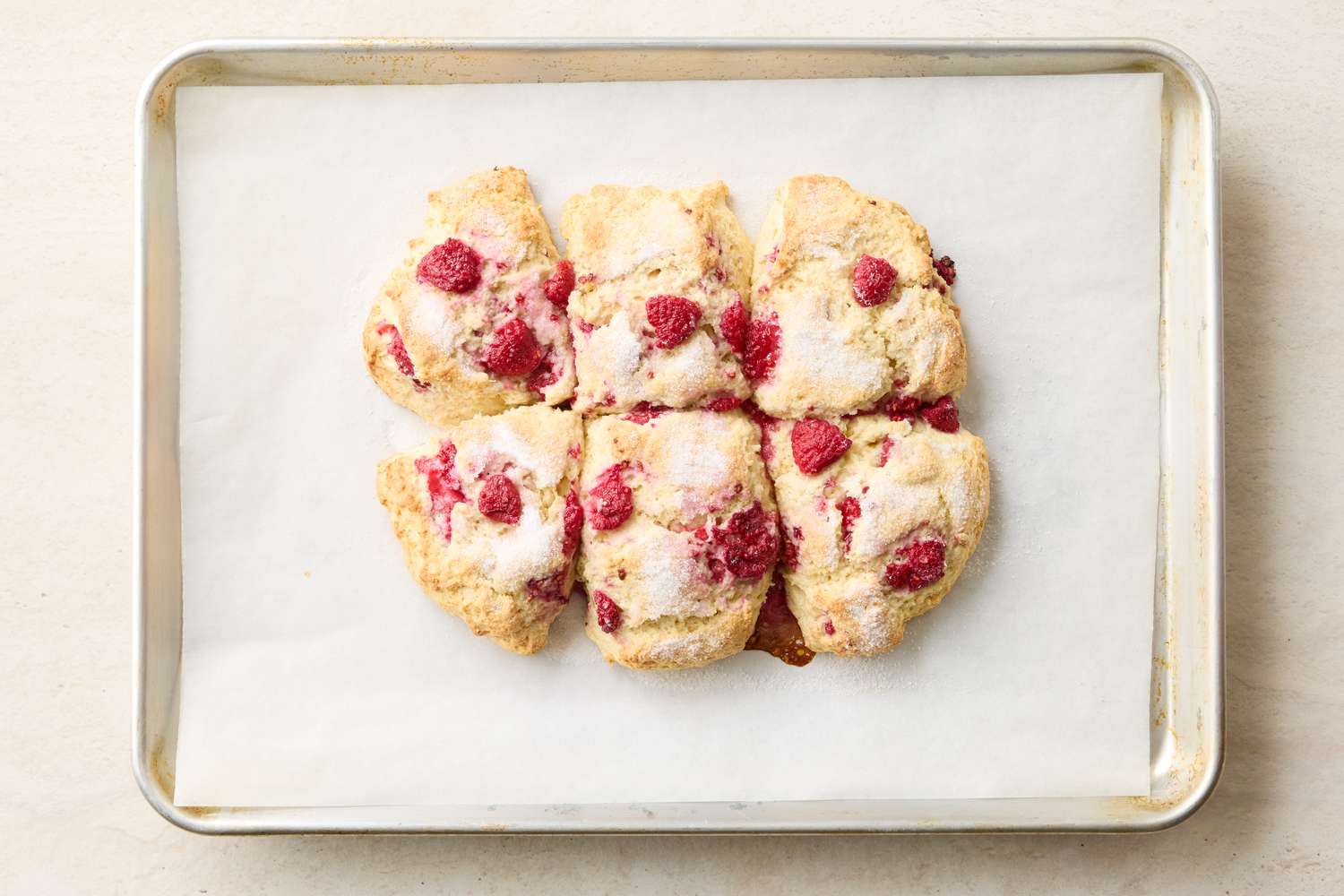 Tray of baked raspberry scones on parchment paper