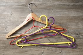 A collection of hangers in various materials including wood metal and plastic lying on a wooden surface