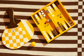 yellow paddle and backgammon set against a striped brown background