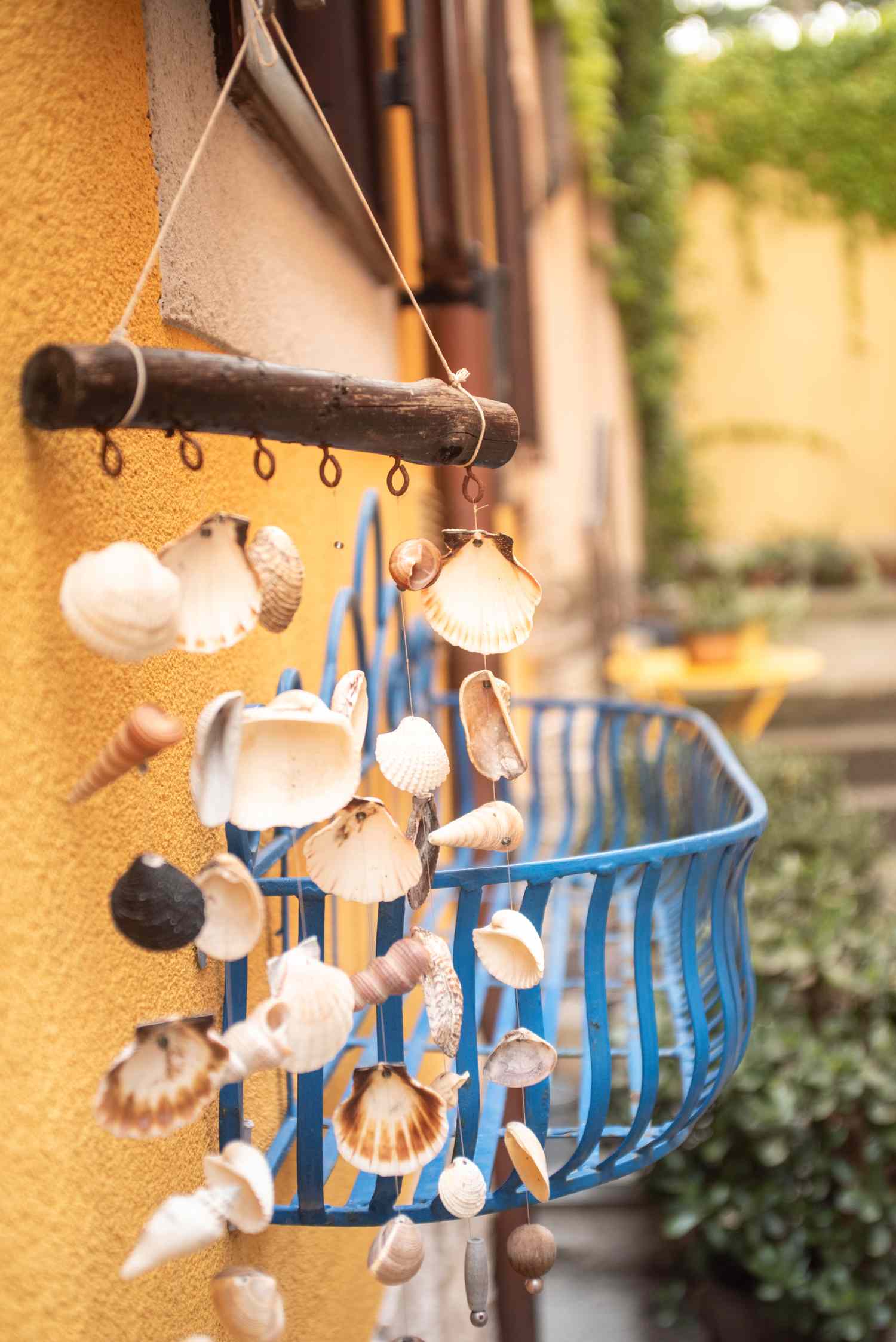 Hanging seashell decoration outside near a wall and basket planter