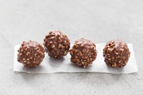 Four chocolate hazelnut truffles on a piece of wax paper