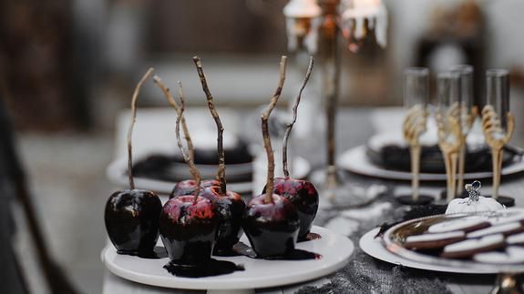 Table setting featuring candy apples on plates and elegant dining decor