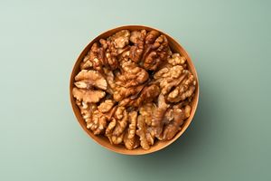 A bowl filled with shelled walnuts on a plain background