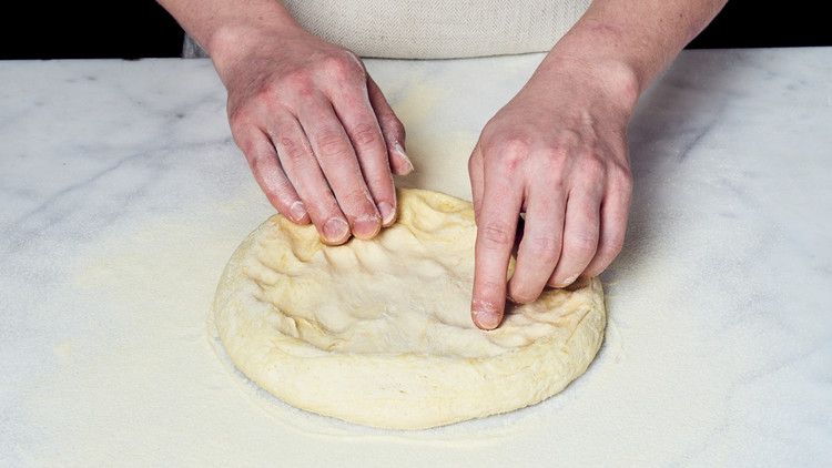 person kneading pizza dough