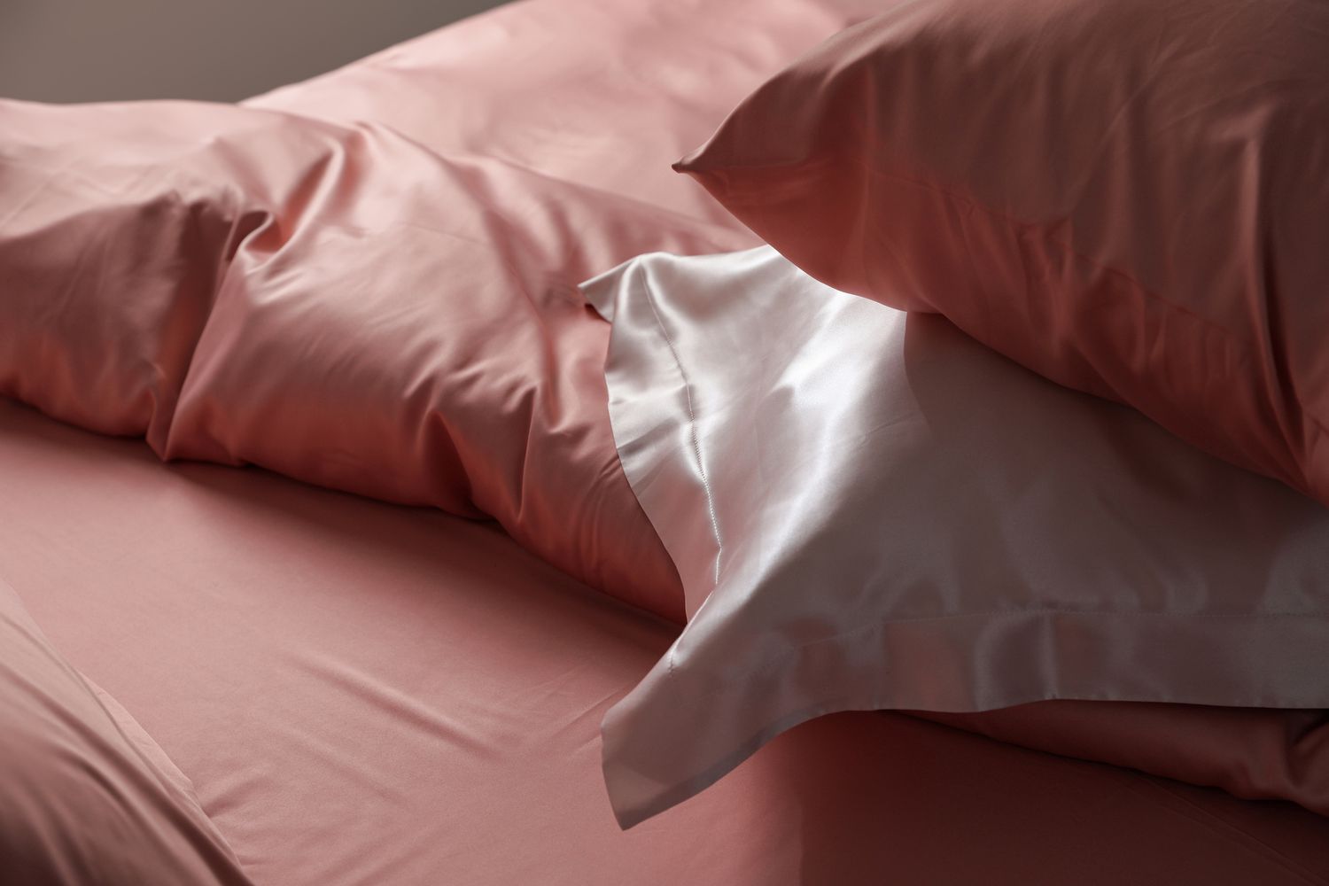 Closeup view of bed with silk pillowcases and linen sheets