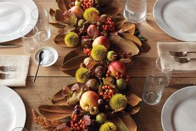 Thanksgiving table centerpiece featuring fruit foliage and decorations with table setting in view