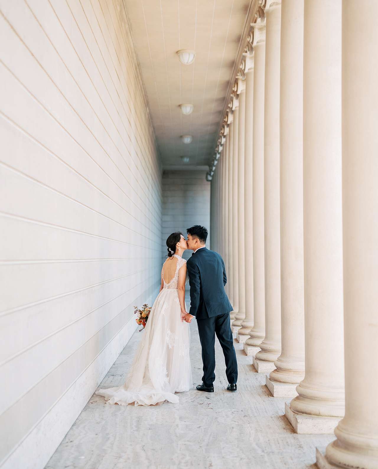 wedding couple kiss near museum pillars
