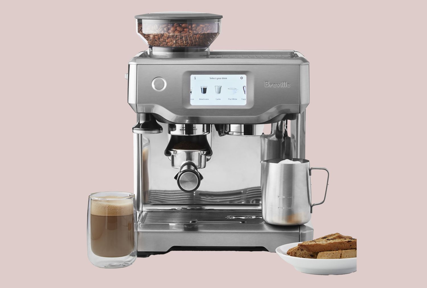 Espresso machine with a milk frothing pitcher a coffee mug and a plate with biscotti