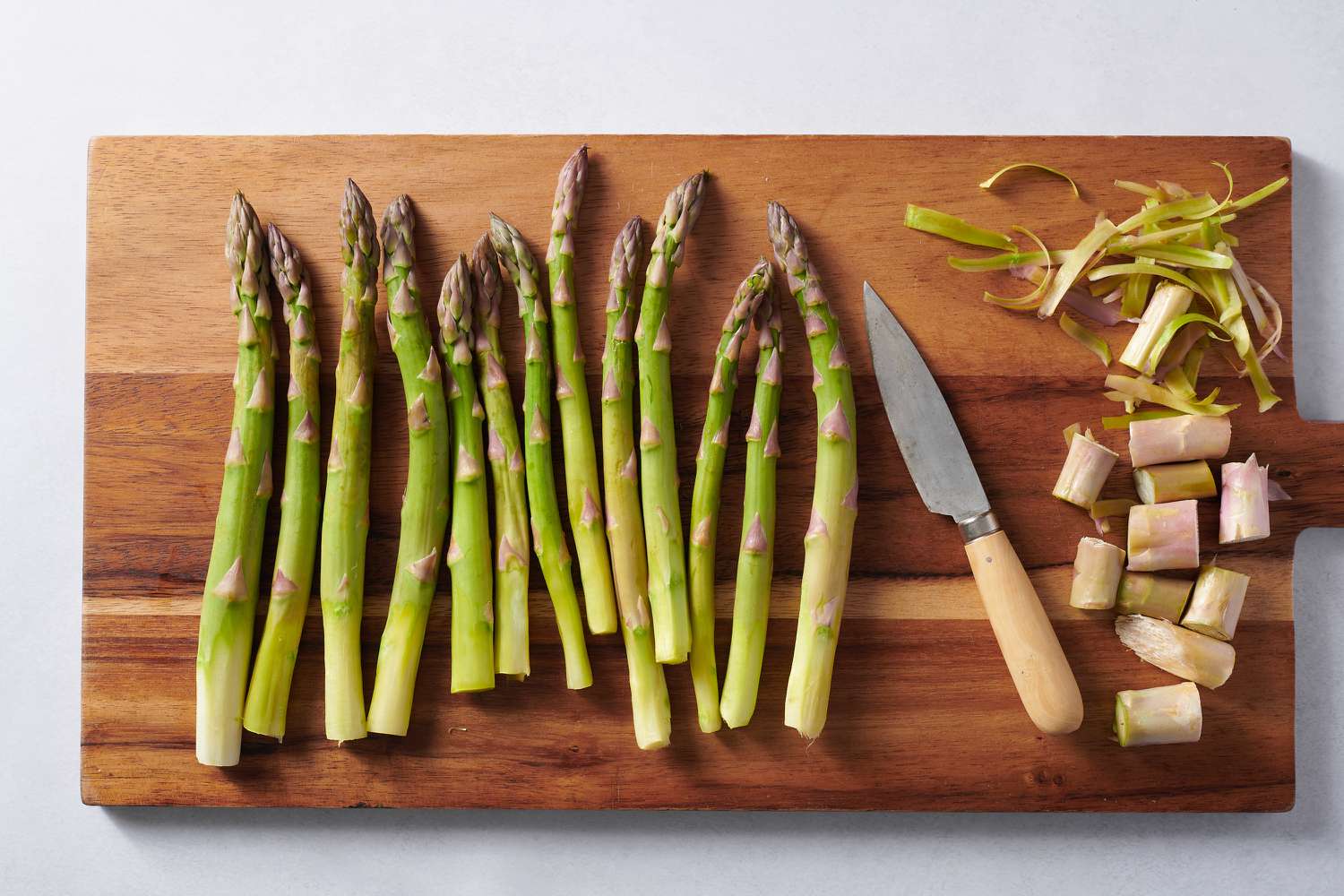 trimming ends of asparagus on a chopping board